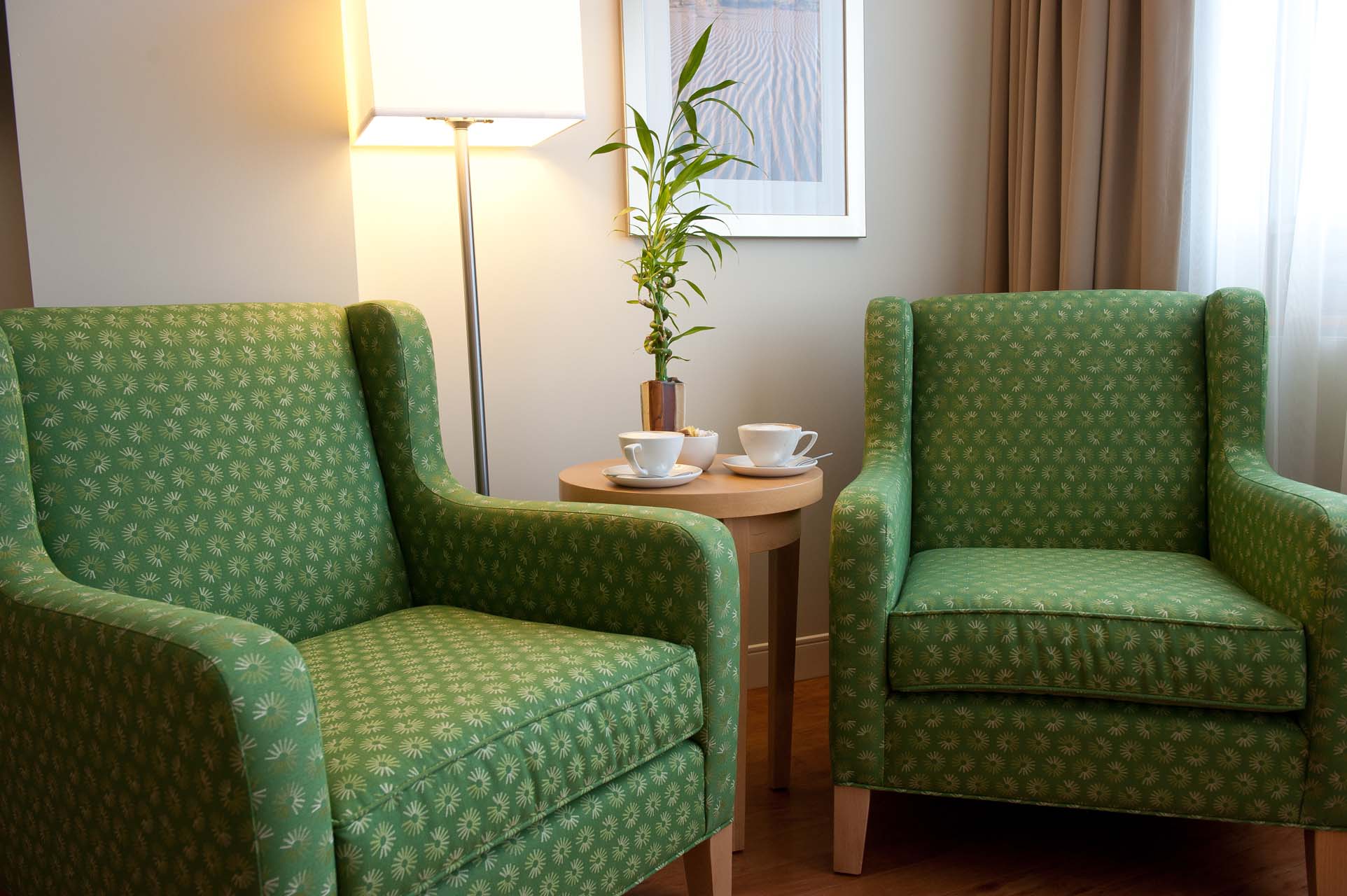 Two green armchairs on either side of a small table