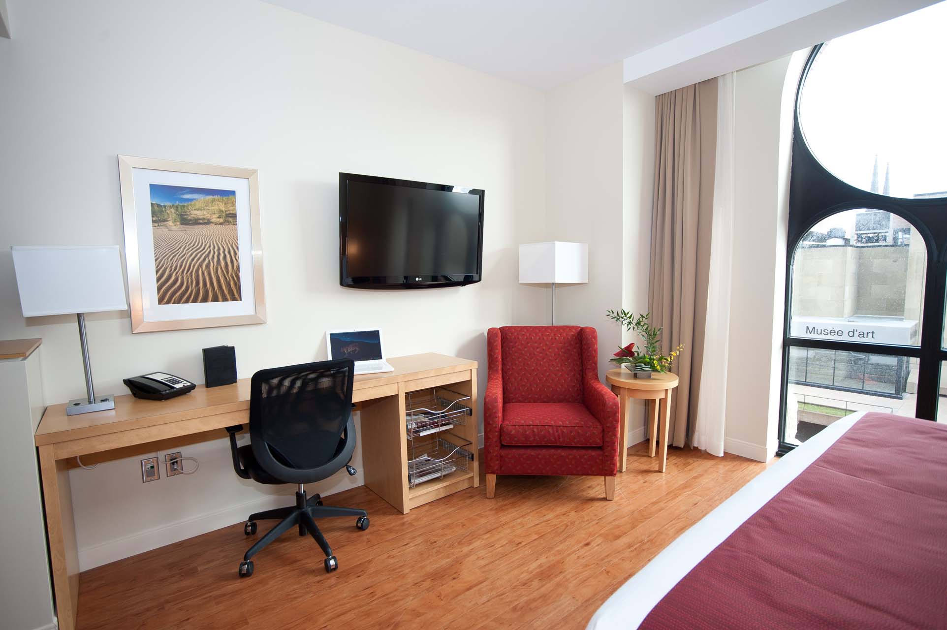 Guest room with a work desk, a TV, and an armchair