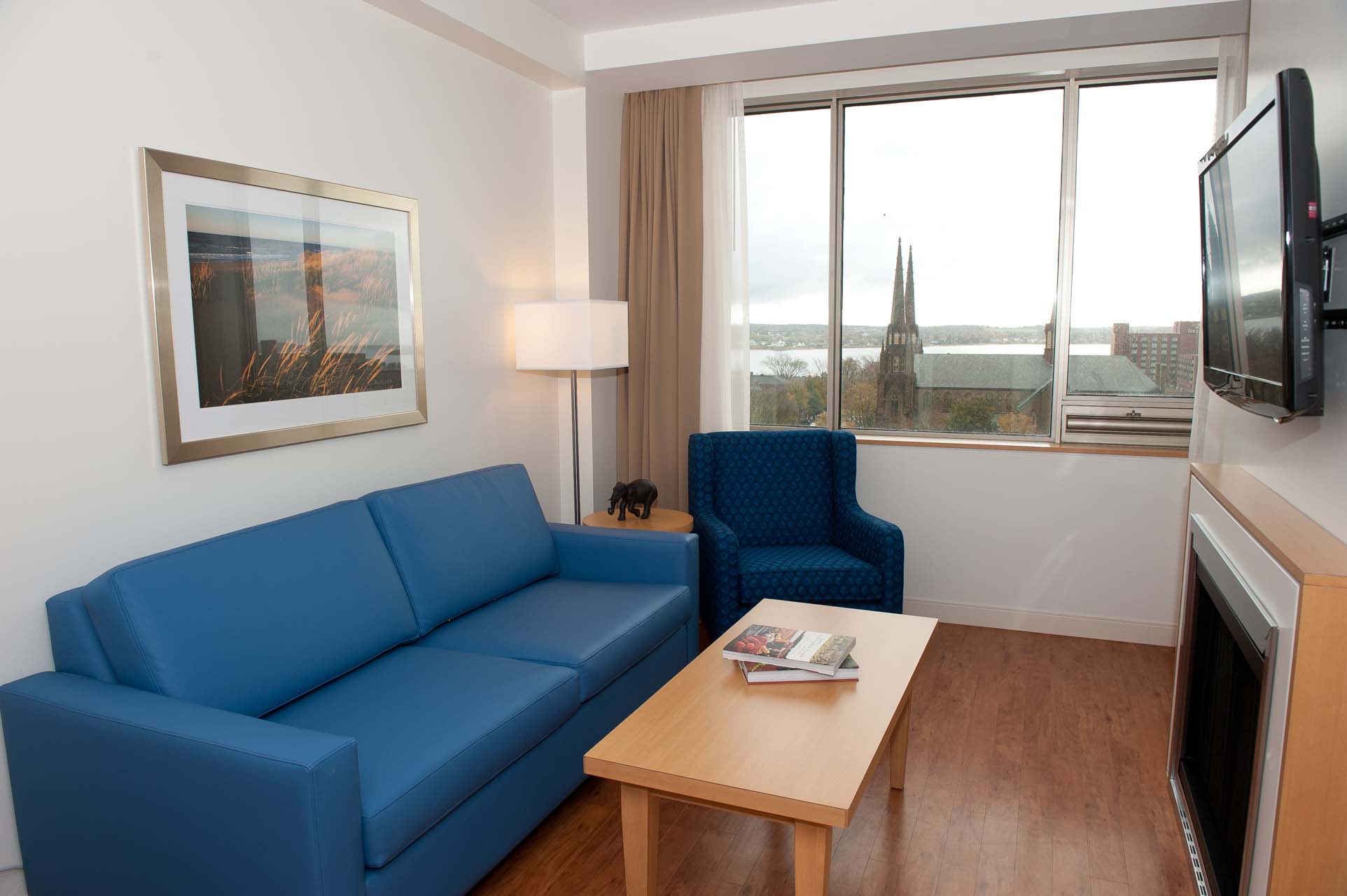 A living room with a blue sofa, a fireplace, and a wall-mounted TV