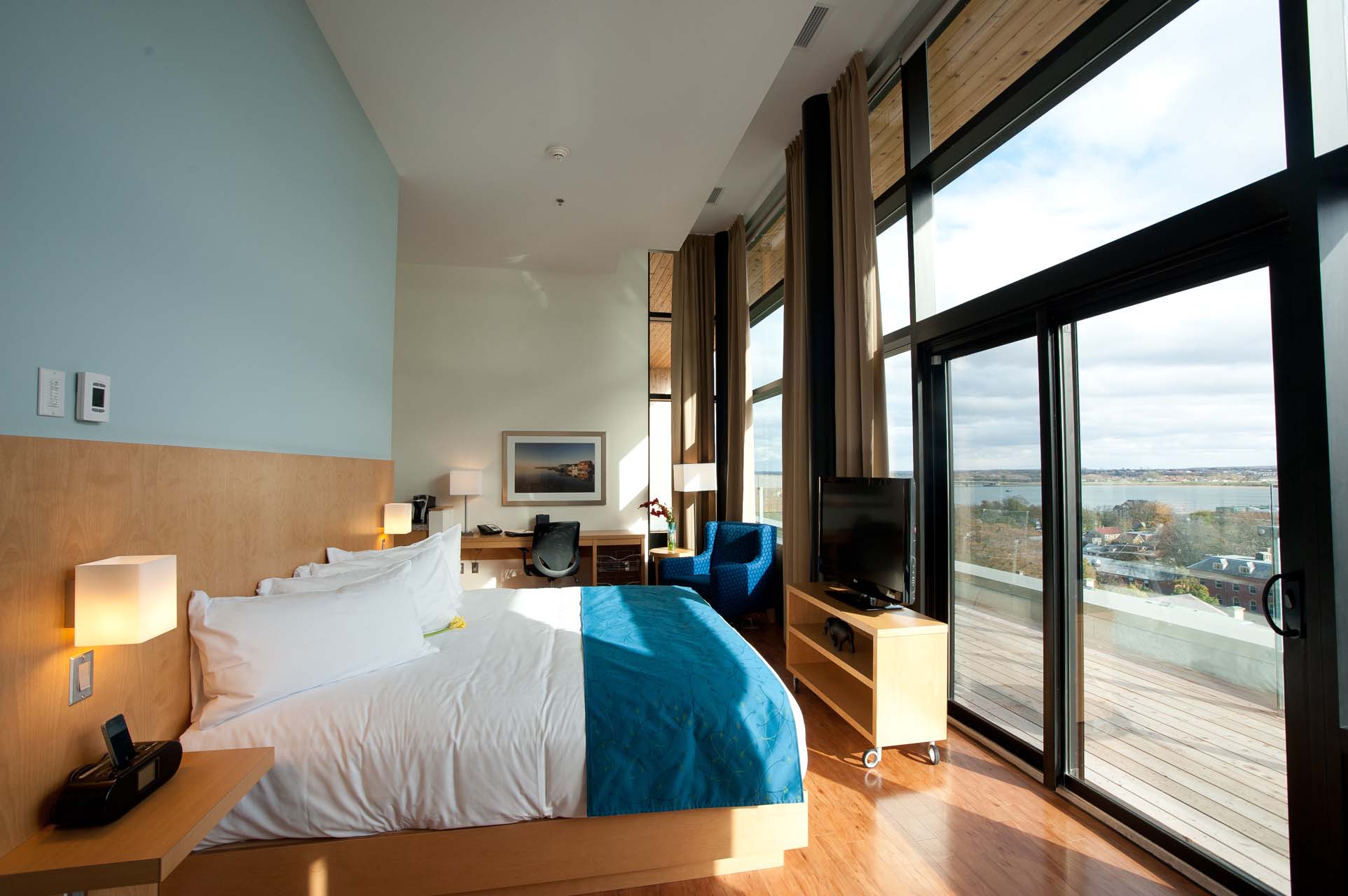 A guest room with a king bed and floor to ceiling windows