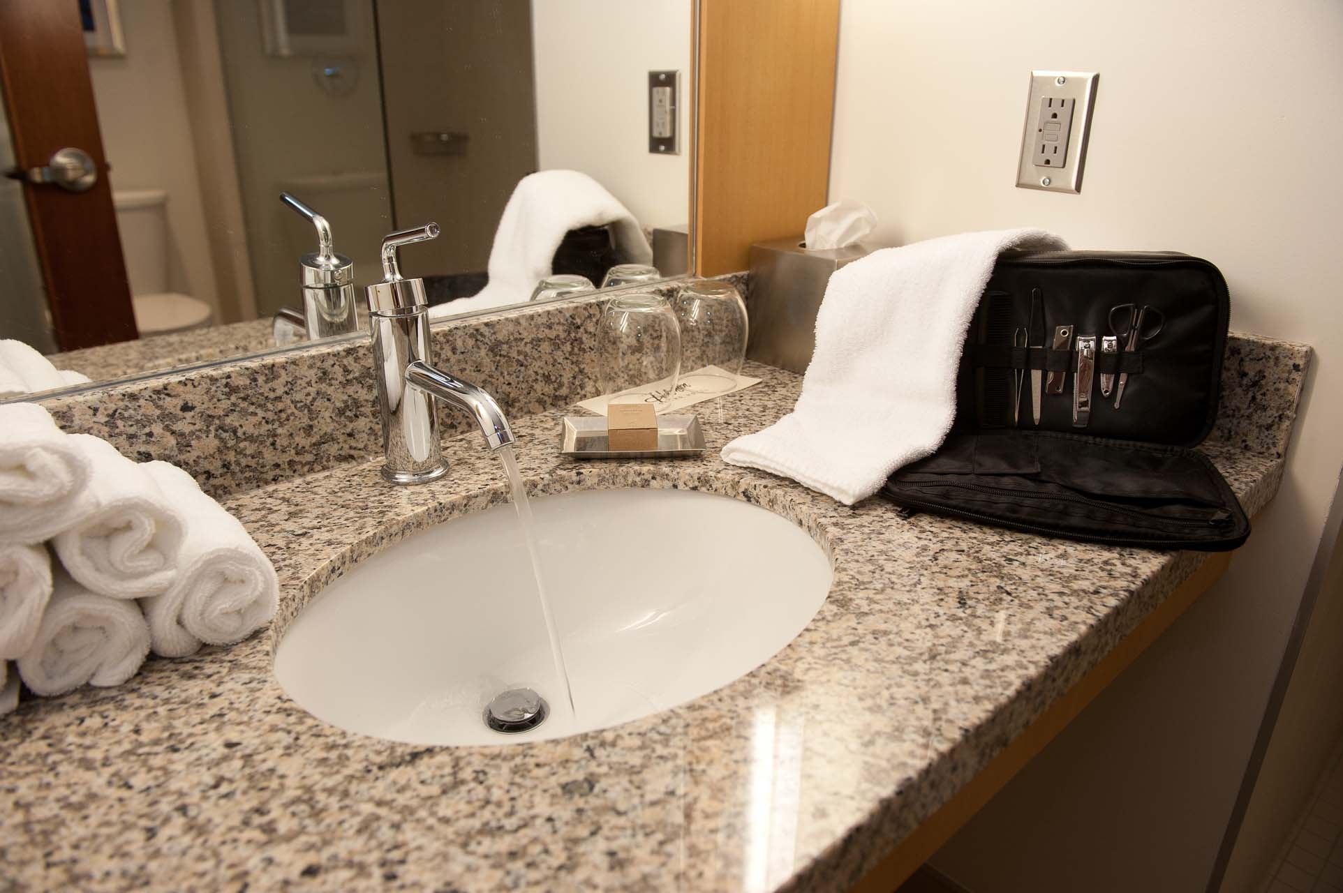 Bathroom sink with a toiletry bag and rolled hand towels