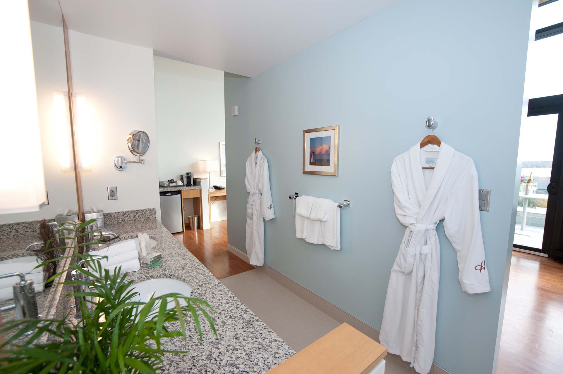 A bathroom with two bathrobes hanging on the wall
